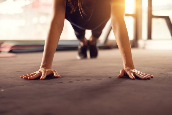 close up woman hand doing push ups exercise in a gym in morning, sunlight effect.