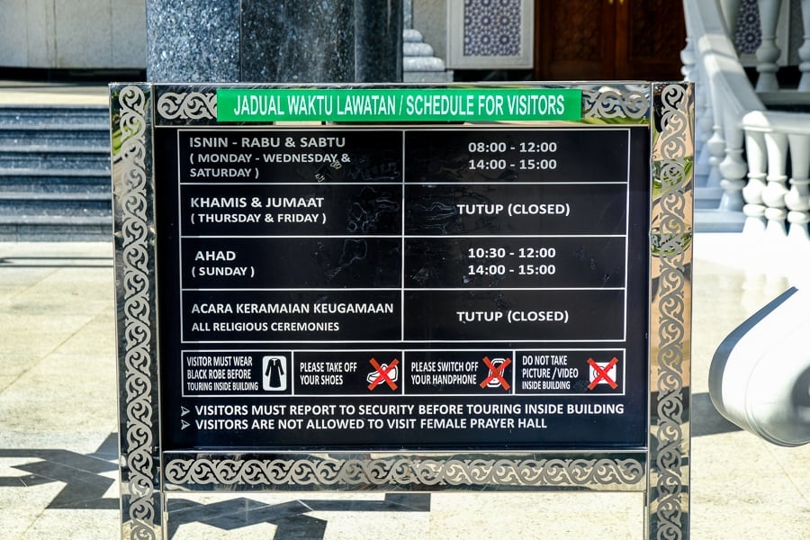 Entrance sign explaining rules and entry times at the Jame'Asr Hassanil Bolkiah mosque in Brunei