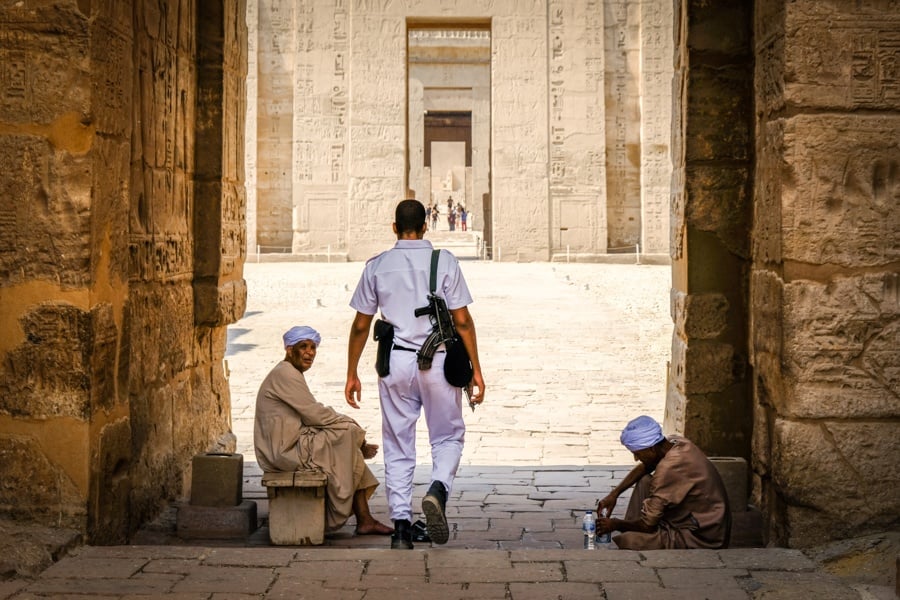 Security guard policeman and beggars at Medinet Habu Temple in Egypt