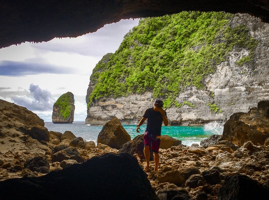 Travel guy inside of the sea cave at Tembeling Beach in Nusa Penida, Bali