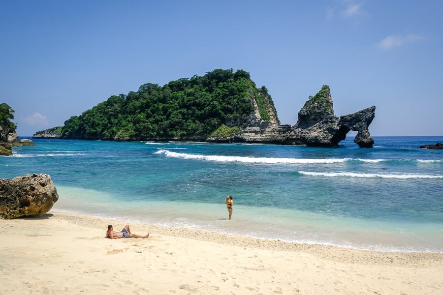 Tourists with their kid playing on the sand at Atuh Beach in Nusa Penida, Bali