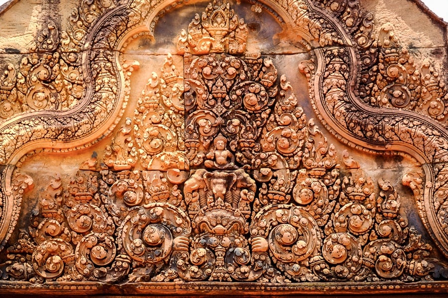 Intricate Hindu carvings in an orange stone wall at Banteay Srei